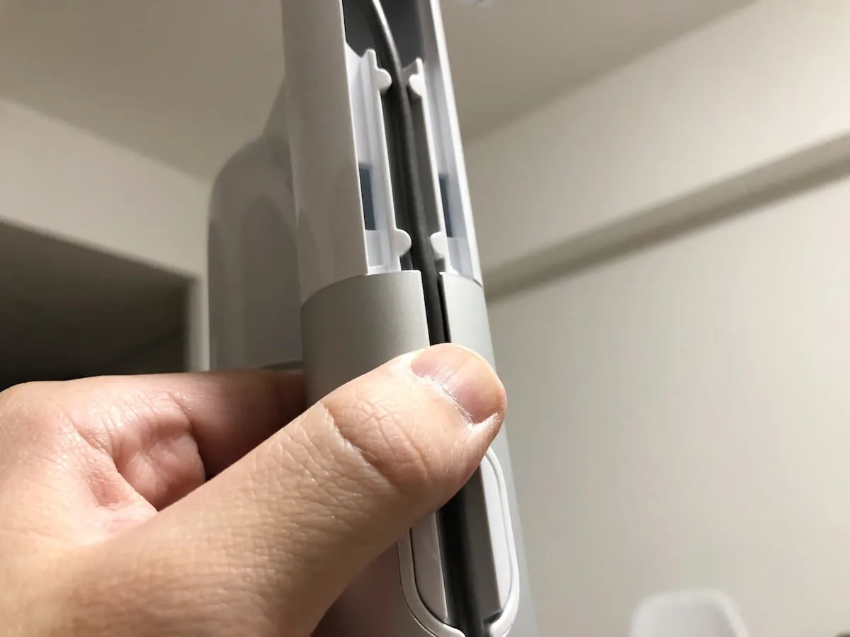 ダイソンのスタンドに充電ケーブルを押し込んでいる様子